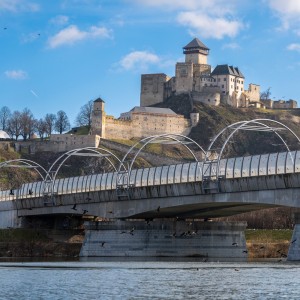 Trenčiansky hrad s novým železničným mostom v popredí a letiacim kŕdeľom vtákov.